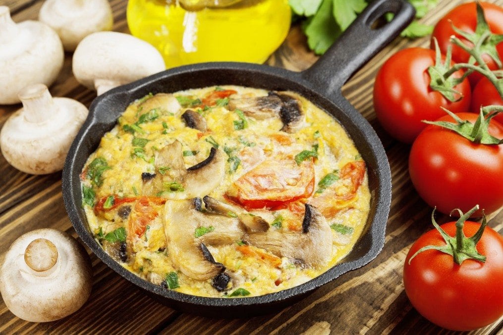 Omelet with mushrooms and tomatoes. Frittata in a frying pan