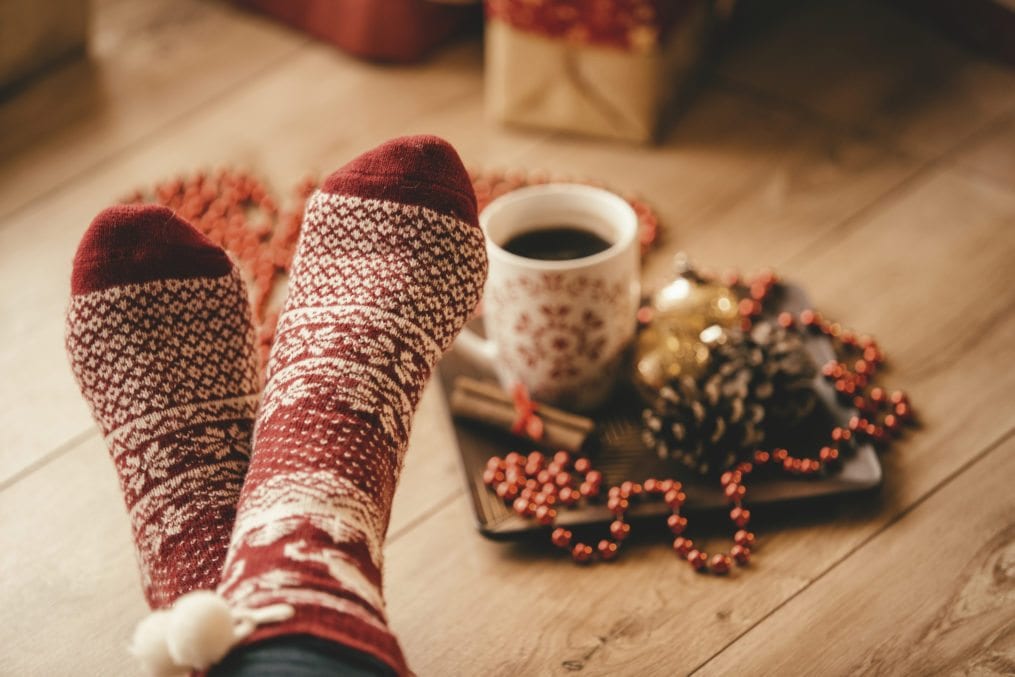 Crossed legs in seasonal winter socks, woman relaxing on Christmas day.