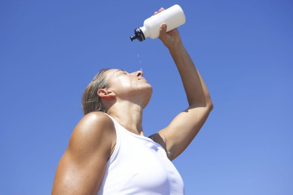 young exhausted athlete pouring water out of bottle