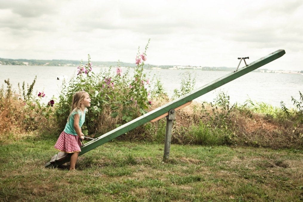little girl playing alone on a seesaw