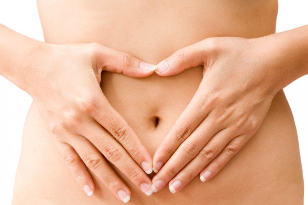 Woman with hands in heart shape over her stomach