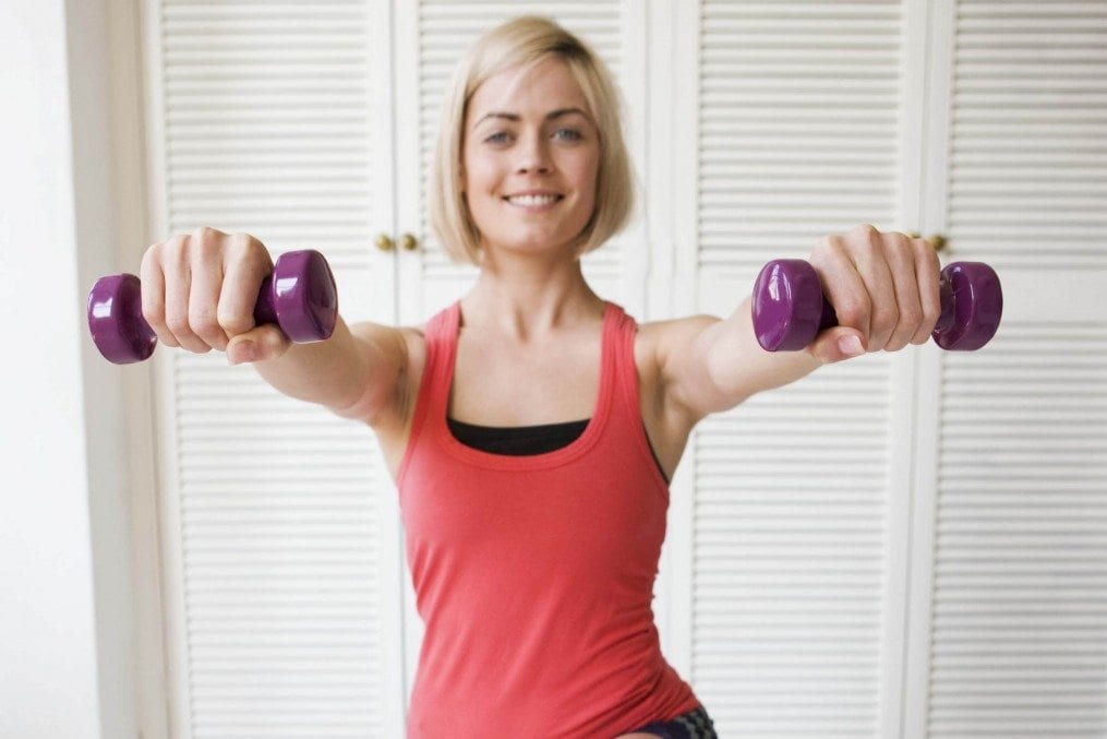 Woman working out with dumbbells at home