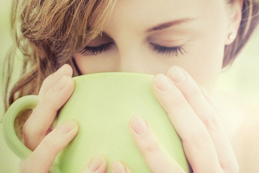 Woman drinking herbal tea from lime green cup