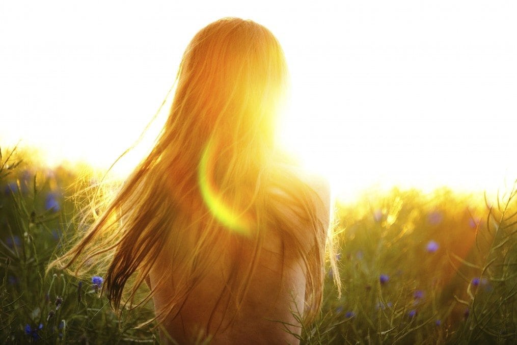 Young woman enjoying sunlight in canola field