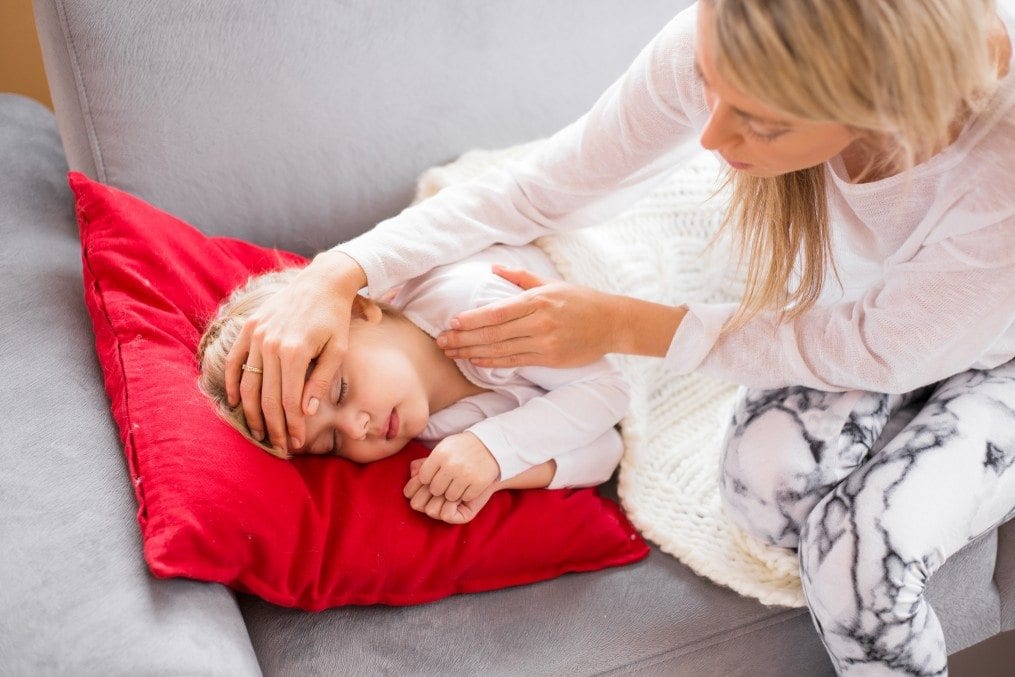 Mother check sick son's temperature with palm