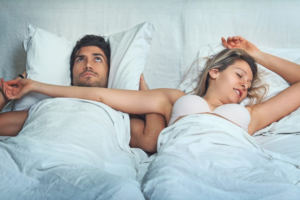 Woman snoring next to her partner in bed