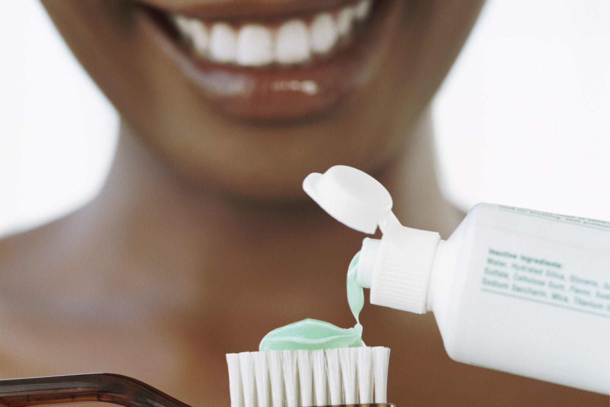 Smiling Young Woman Squeezing Toothpatse onto a Toothbrush