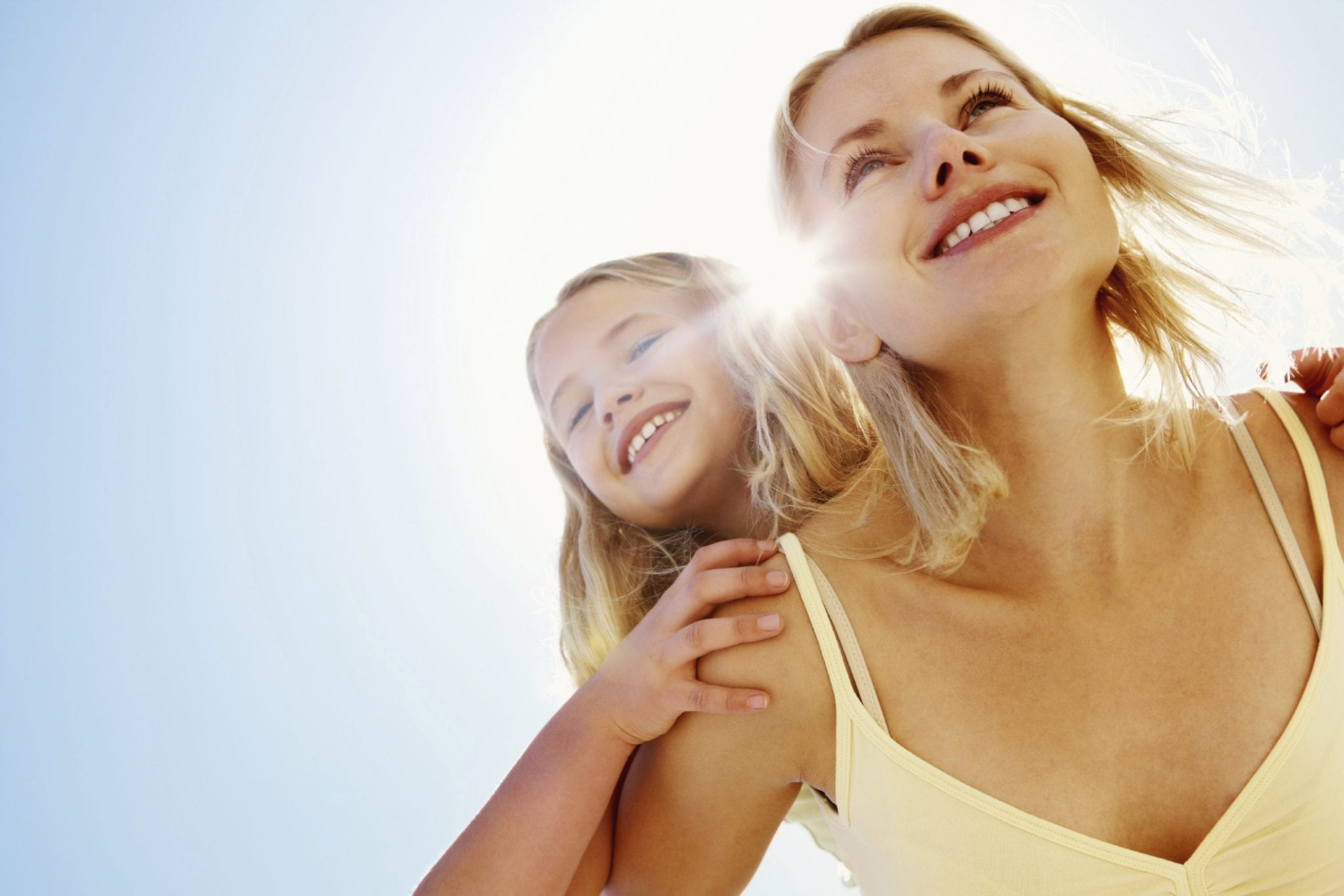 girl being piggybacked by mother on a sunny day