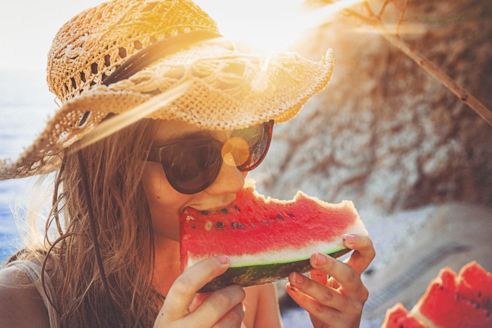 Young woman eating watermelon on beach