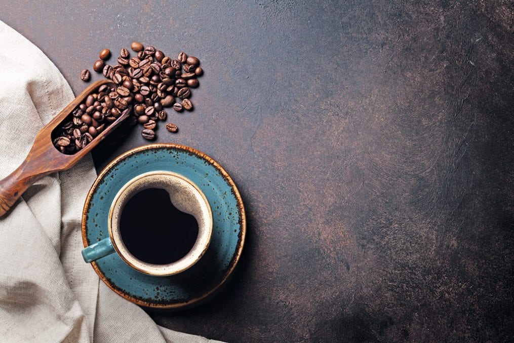 cup of coffee alongside coffee beans