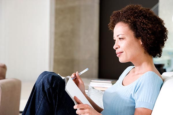 Woman on couch writing a list